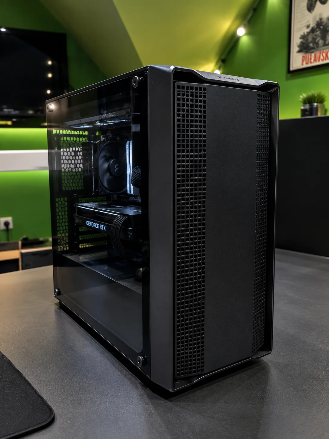 Czarny komputer PC ze szklanym panelem i kartą GeForce RTX na biurku w zielonym pokoju
